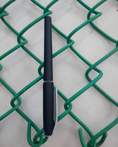 Una pluma negra se coloca en el PVC verde cubrió la cerca de la alambrada y la longitud de dos agujeros es equivalente con la longitud de una pluma.